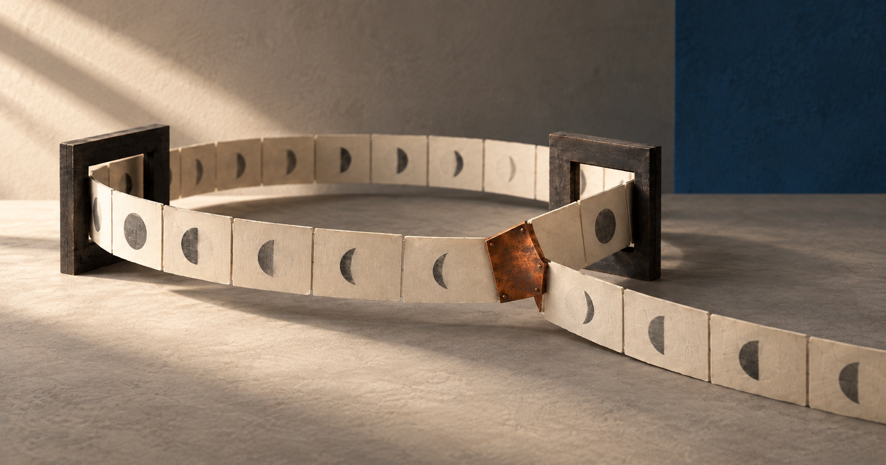 An ivory paper ribbon bearing dark circular shapes loops through two charcoal frames. At a copper junction, another strip branches toward the foreground.
